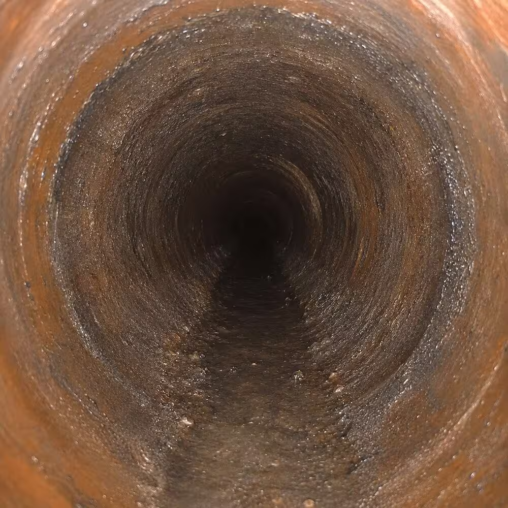 Drain line after professional cleaning with better flow and normal pipe wear still visible.