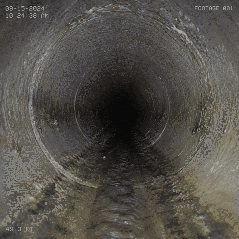 Sewer camera footage traveling through the inside of a residential sewer pipe